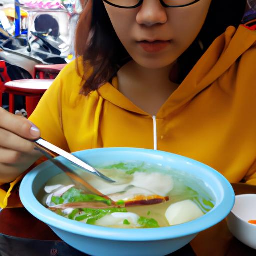 Một phụ nữ thưởng thức bát Bún chả cá tại quán ăn đường phố ở Đà Nẵng